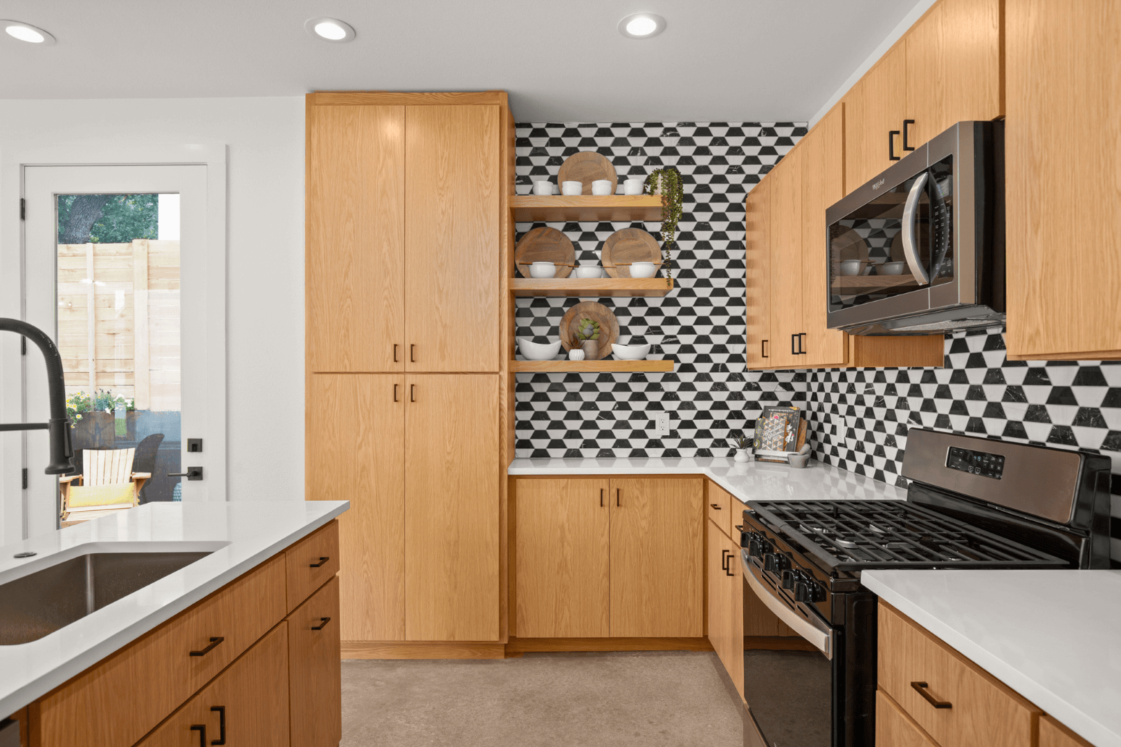 Wooden cabinets, stainless steel microwave and stove, and a white quartz waterfall island in a new construction in Austin, TX.