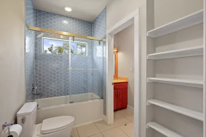 New blue tiles in shower and new shelves for storage spaces featured in this bathroom renovation.