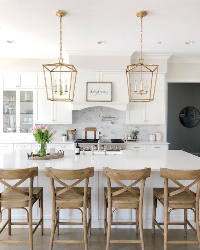 A white kitchen with island and marble backsplash in a custom-built home