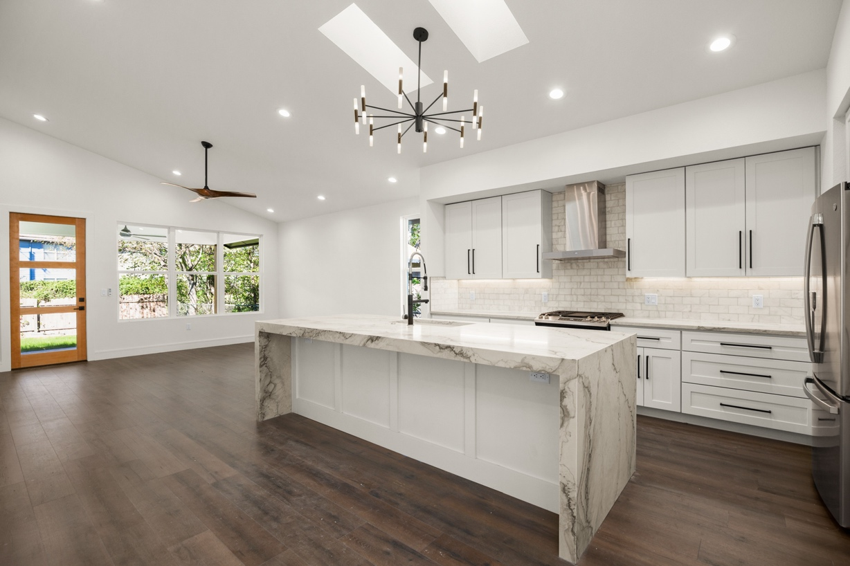 a renovated kitchen with white cabinets and white marble countertops