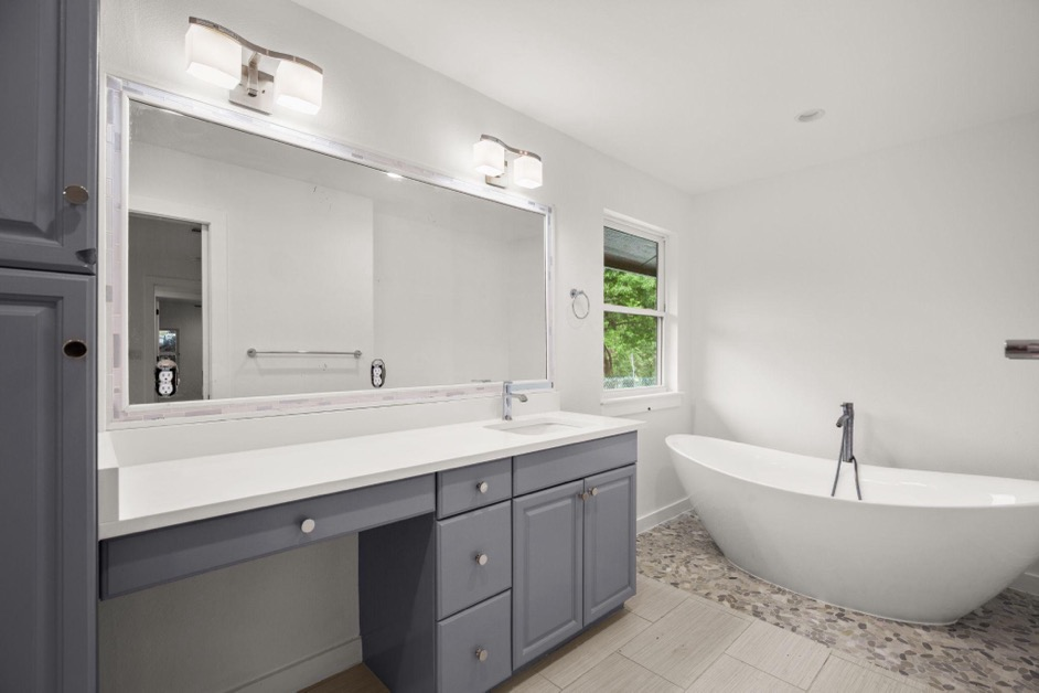 A bathroom storage solution with under-sink cabinets, a bathtub, and a mirror.