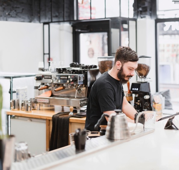 a barista makes coffee in a shop built by commercial contractors