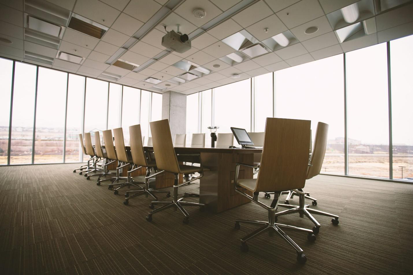 A meeting room with a table, chairs, and windows