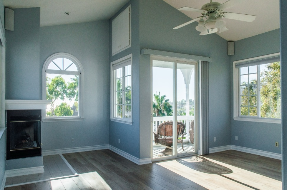 The interior of a new room addition with wooden floors, blue walls, and a mini fireplace in the corner. 