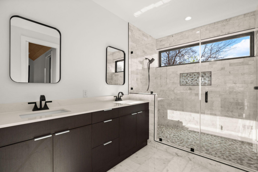 A remodeled bathroom with mirrors, sinks, and a shower space