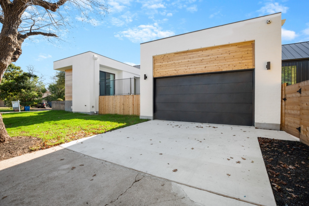 A white custom home in Austin with a brown garage door and wood overhangs.