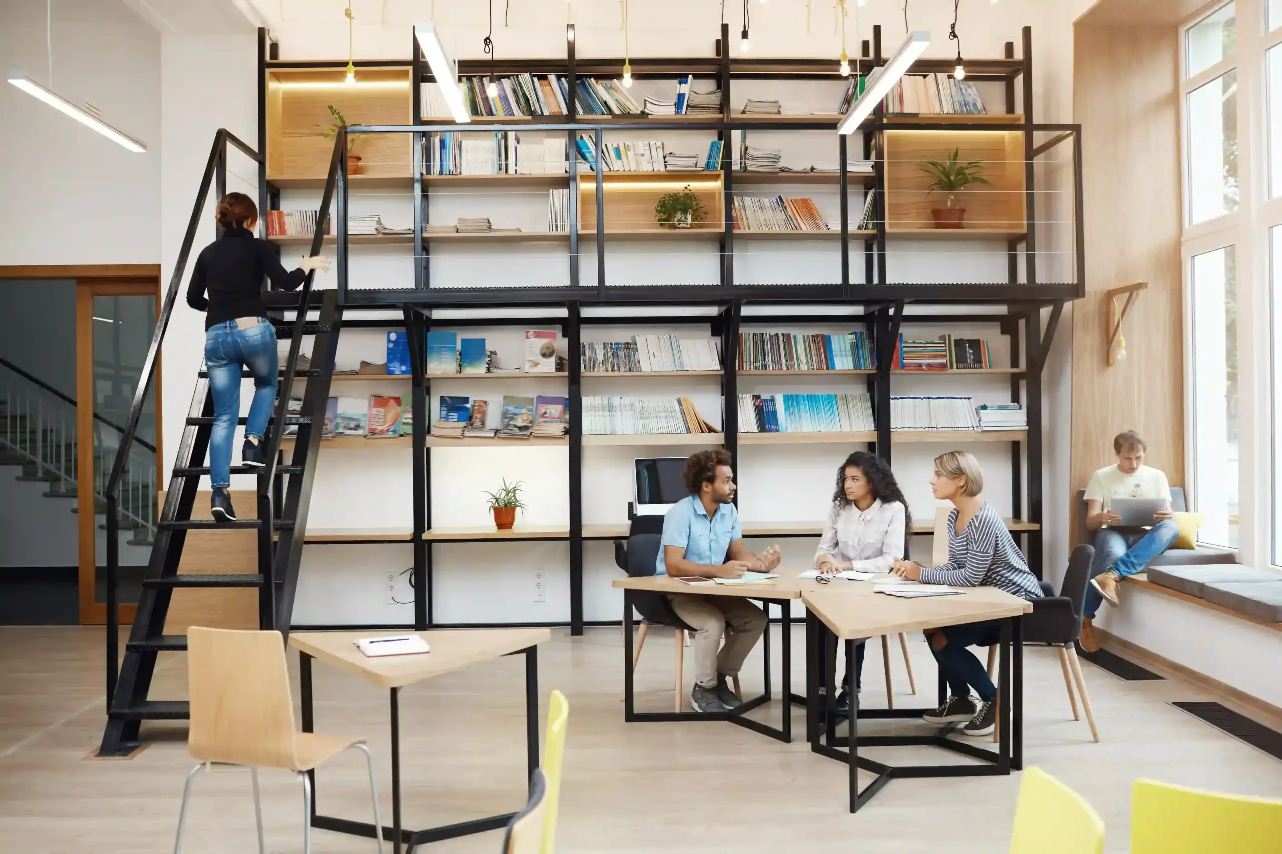 three-young-perspective-startupers-sitting-modern-light-library-meeting-talking-about-new-project-looking-though-details-work-having-productive-day-friends-atmosphere-scaled