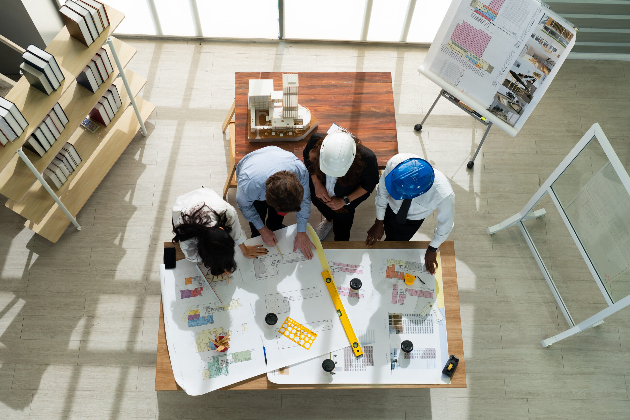 A team of builders and designers gather around floorplans for a commercial construction project