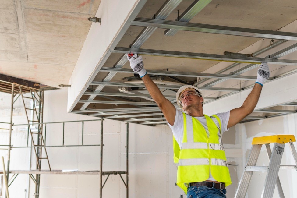 a man builds a frame for lighting and HVAC systems in an office build-out project 