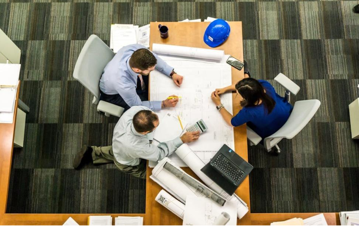 three people sit around a table planning a construction project