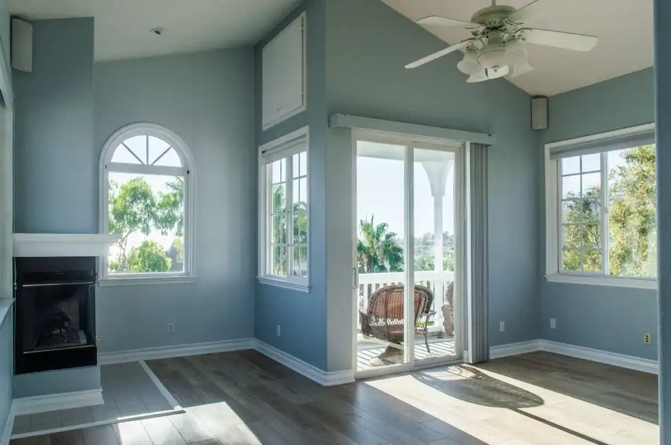 The interior of a new room addition with wooden floors, blue walls, and a mini fireplace in the corner.