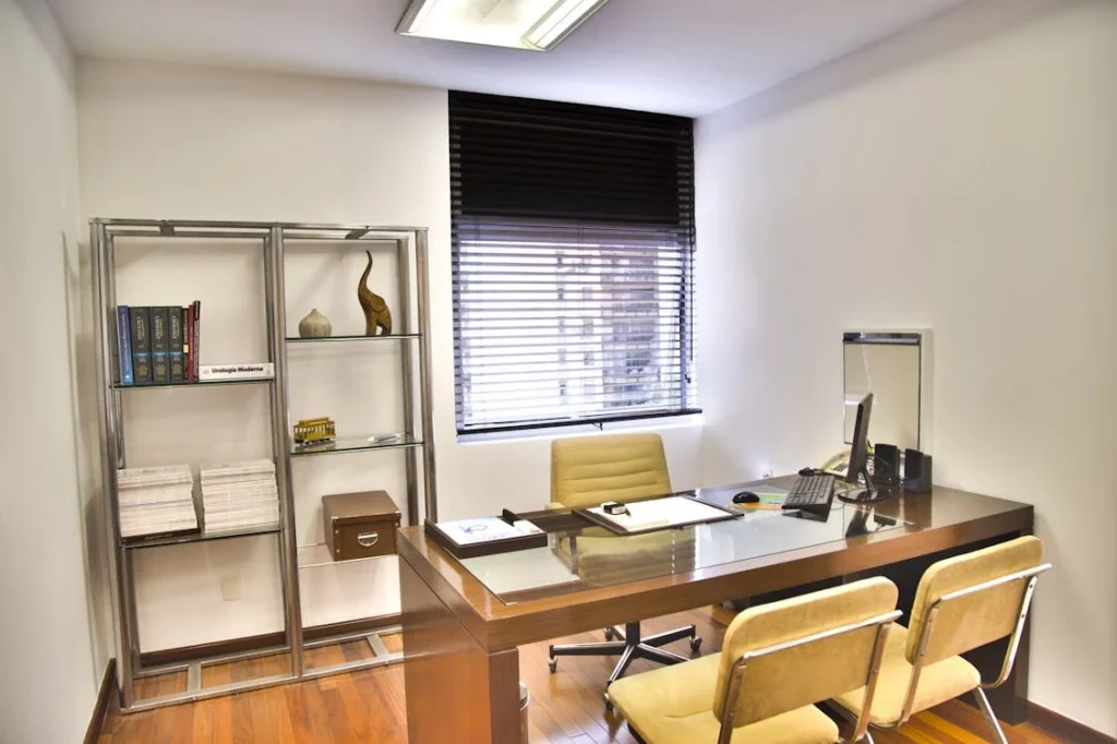 An office room with a desk, chairs, shelves, and a window