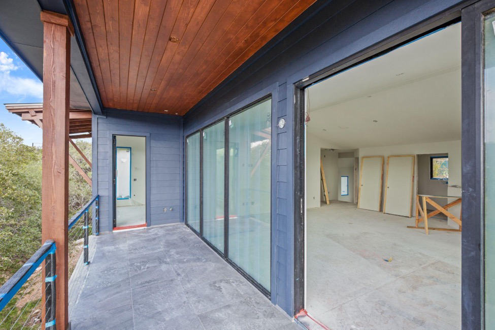 A home’s balcony and adjacent room with huge windows and doorways under construction.