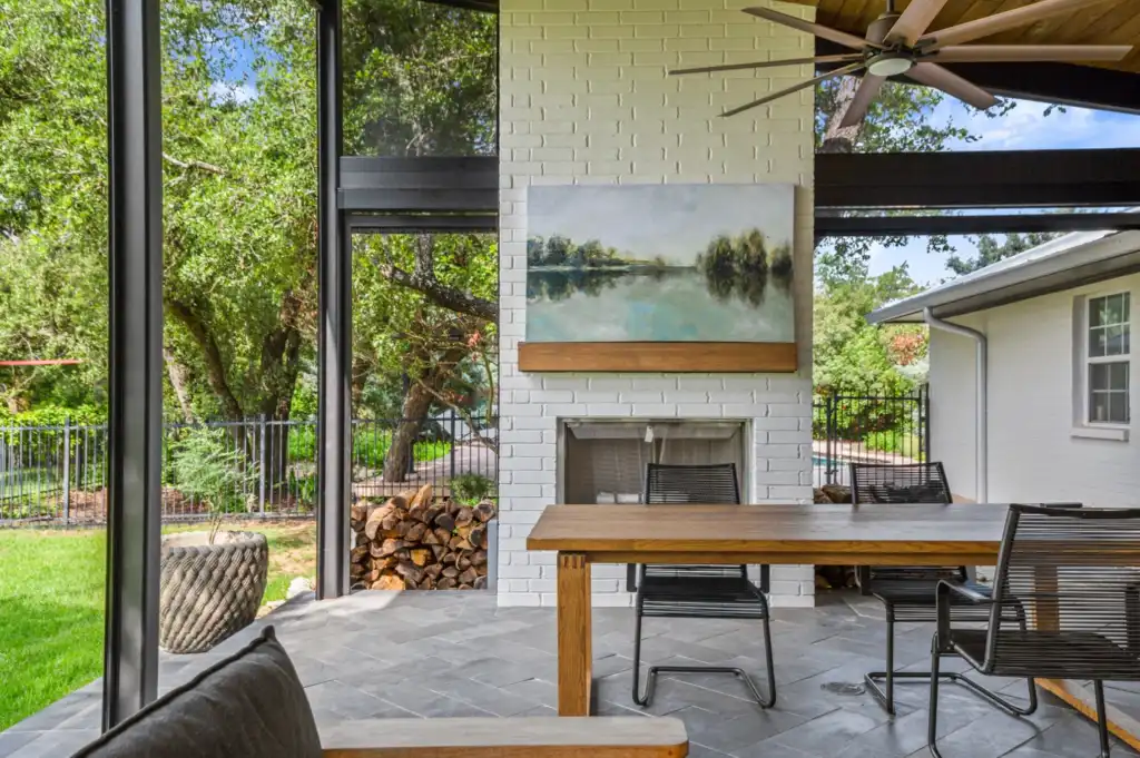 An outdoor room addition with gray paver floors and an outdoor fireplace.