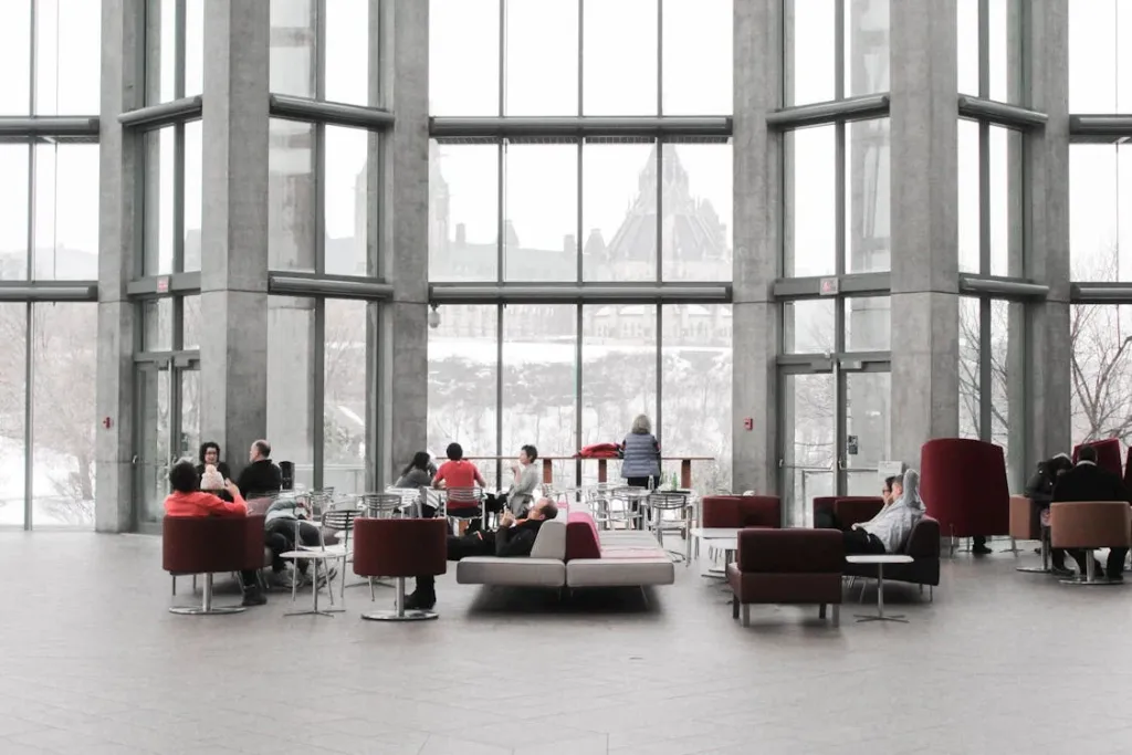 People seated in couches in a commercial space with large windows