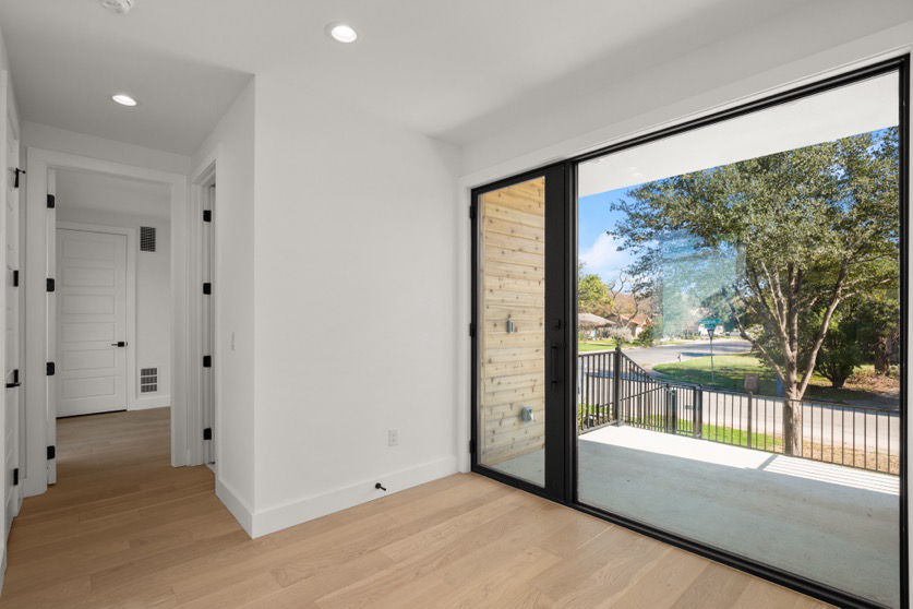 A room addition with wood floors and floor-to-ceiling window and sliding glass door.