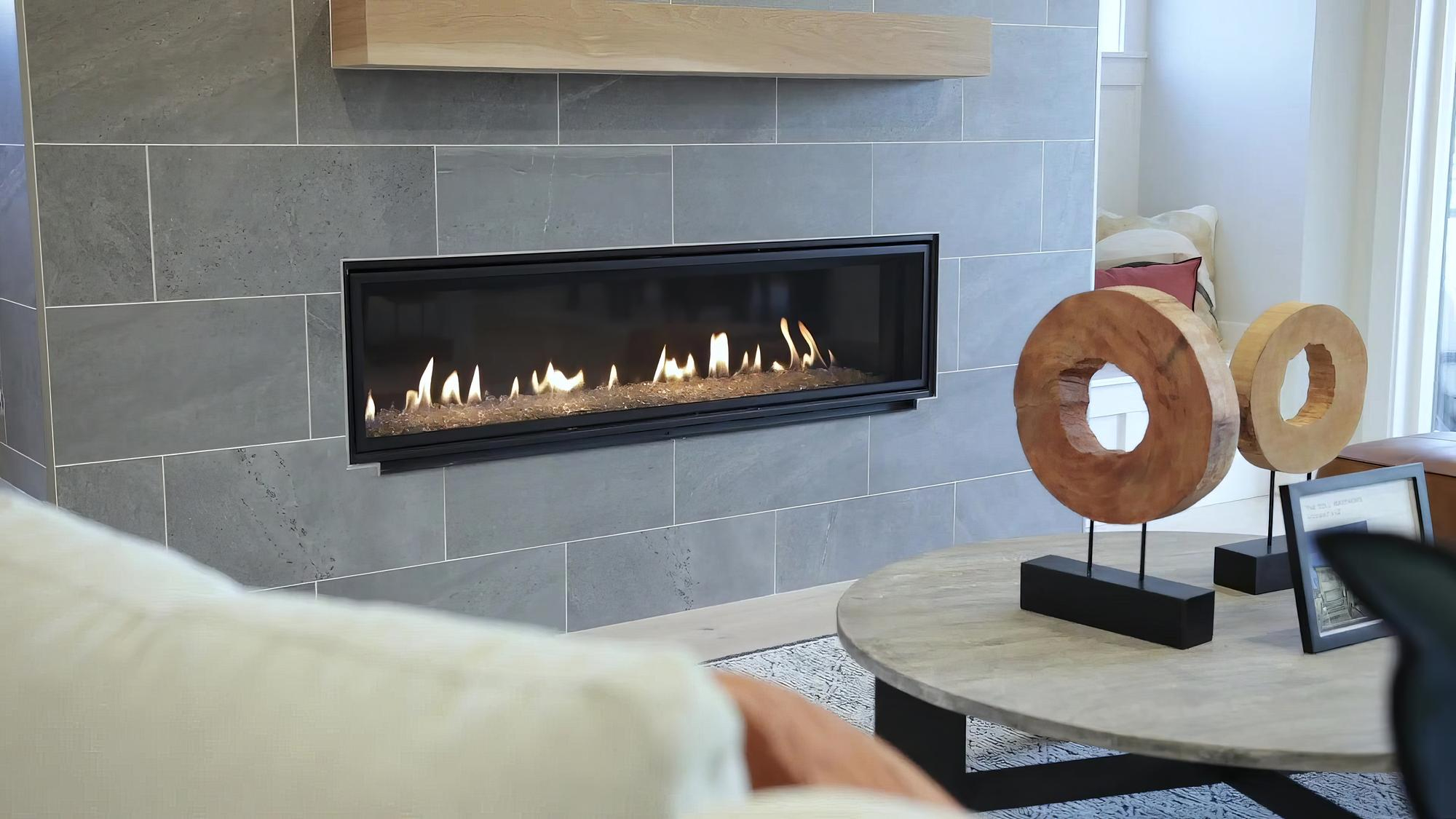 A flaming gas fireplace with blue-gray tile around it in a modern home.