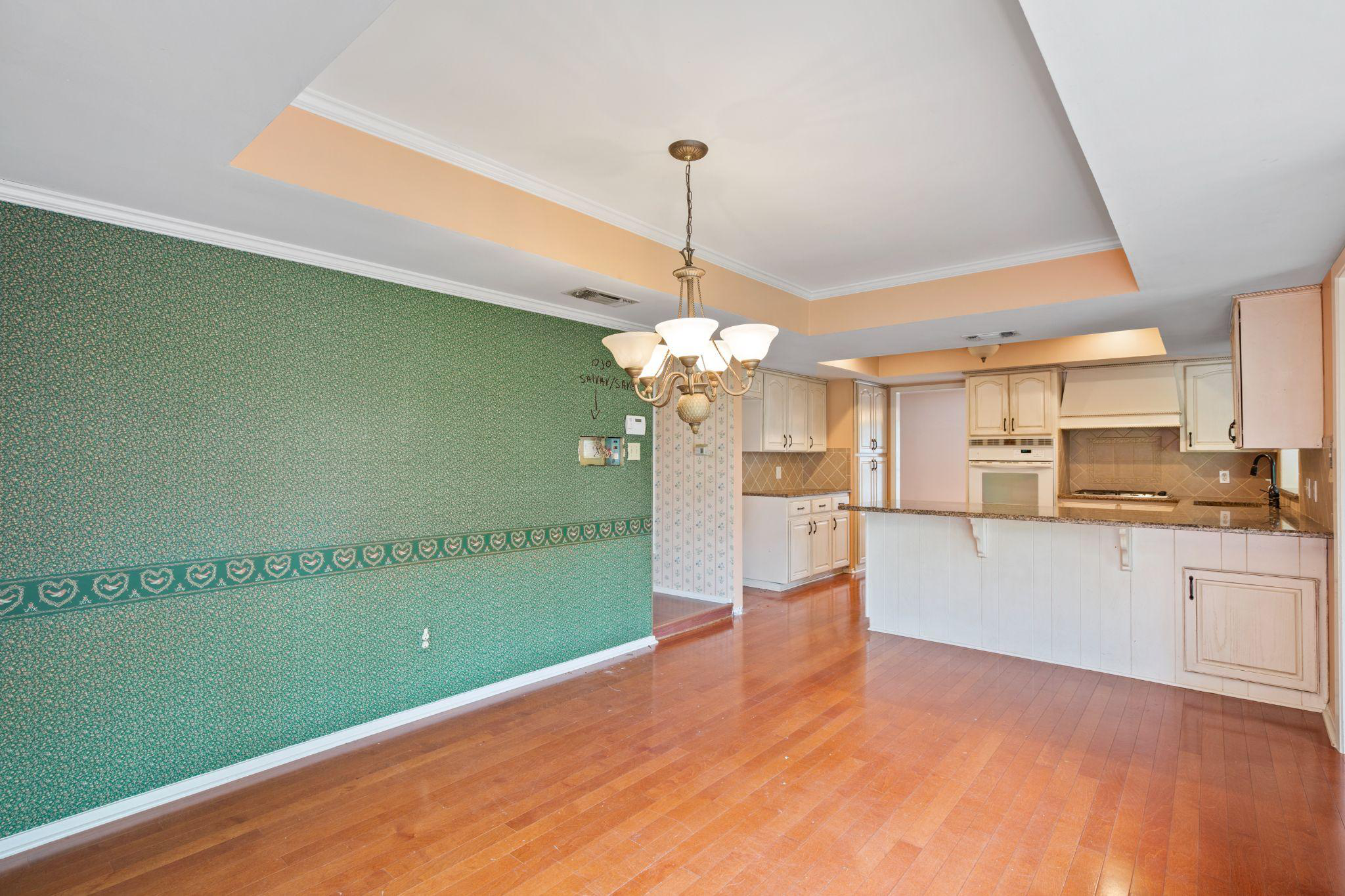 A room with an attached kitchen and a ceiling lamp