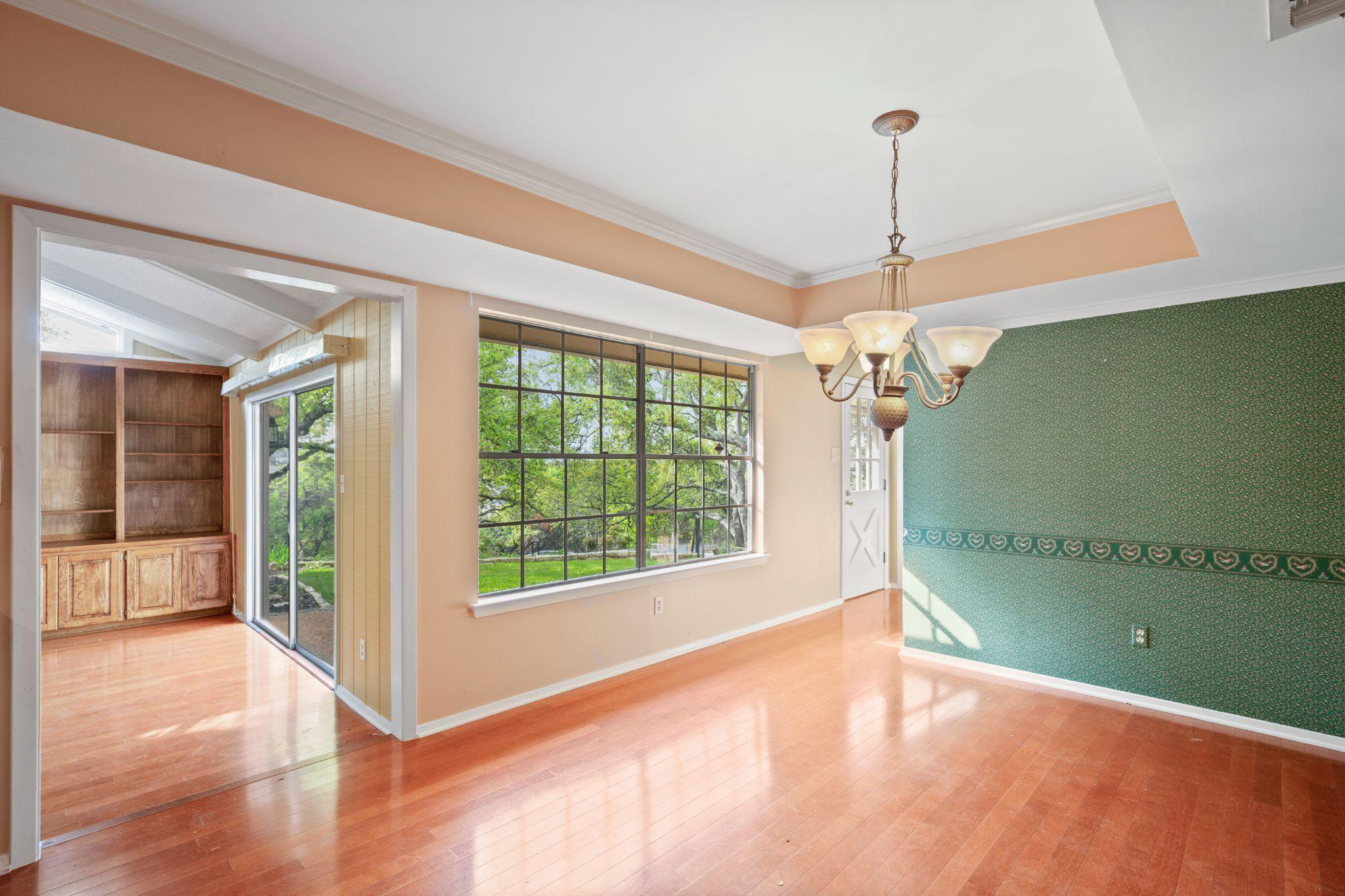 A room with large windows, shelves, a ceiling light, and wooden flooring