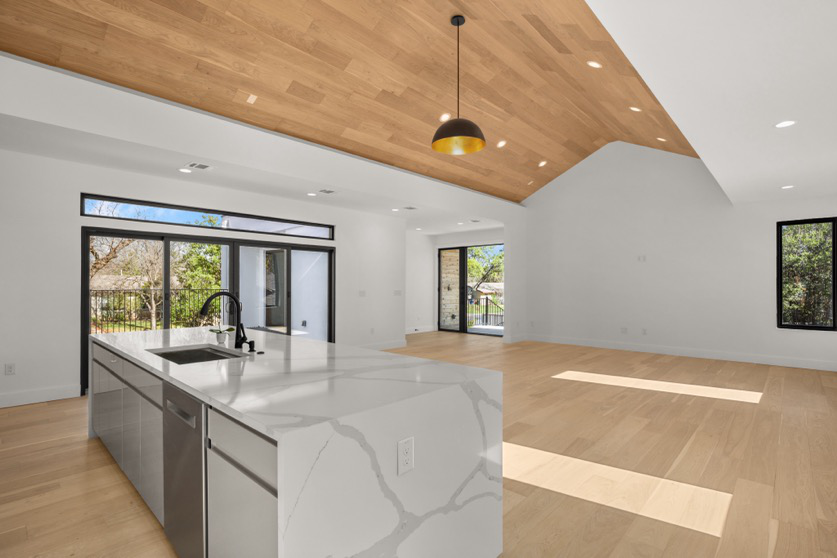 A great room with classic walls, lighting, island kitchen, and a neutral wood floor