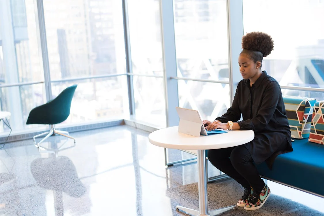 A person working on a tablet inside an office with glass walls