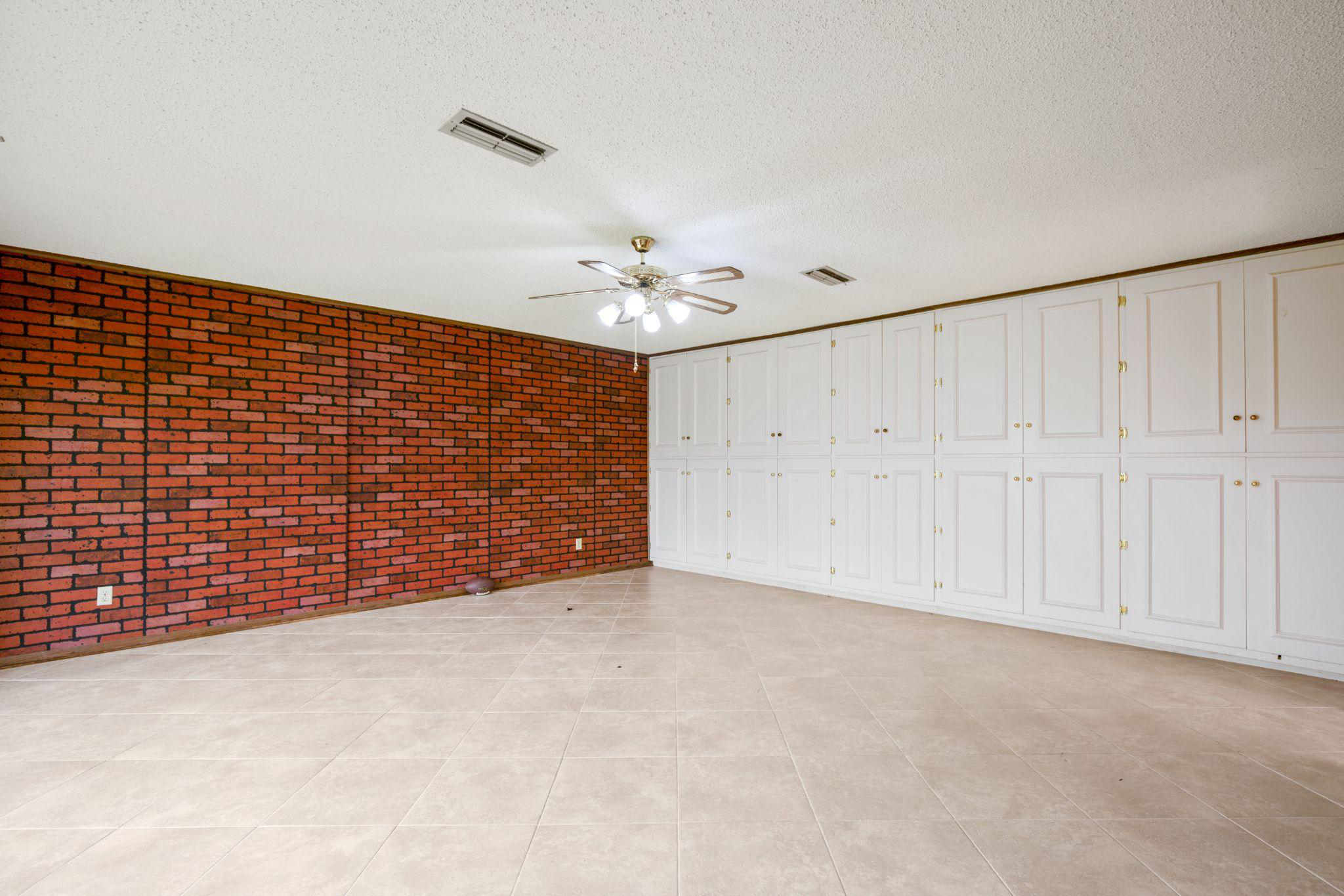 A room with ancient walls, lighting, cabinets, and a neutral floor