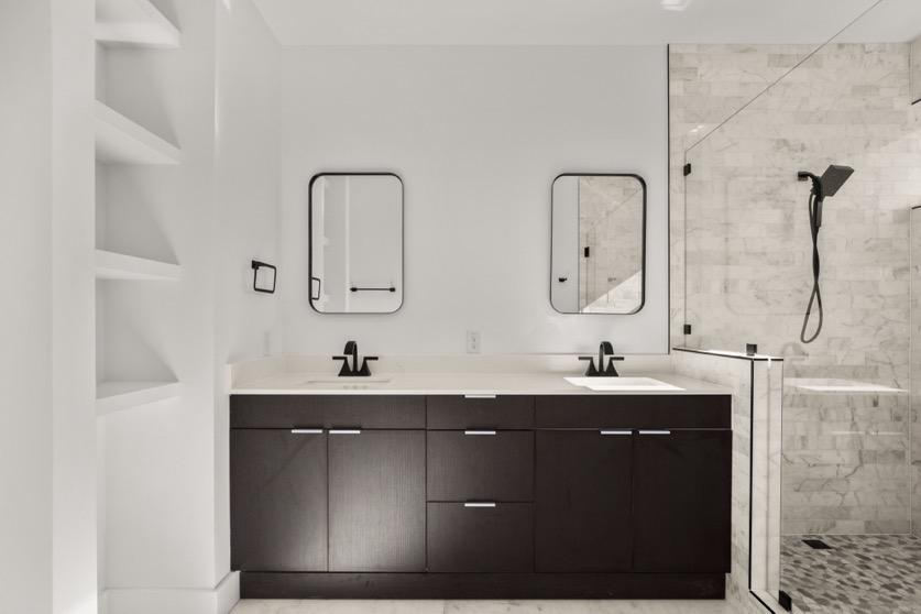 A white bathroom with a walk-in shower and storage shelves.