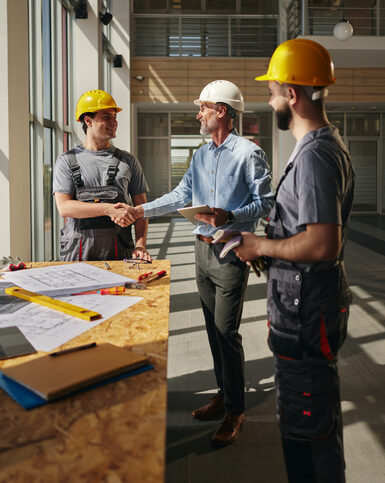 Happy project manager greeting a construction worker in the building.