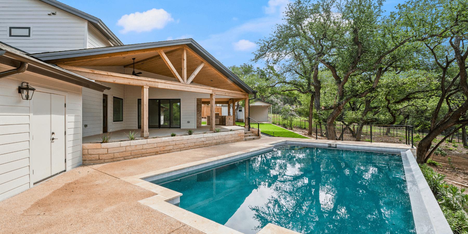 Backyard with modern pool, covered patio, and surrounding trees creating a private, inviting outdoor space