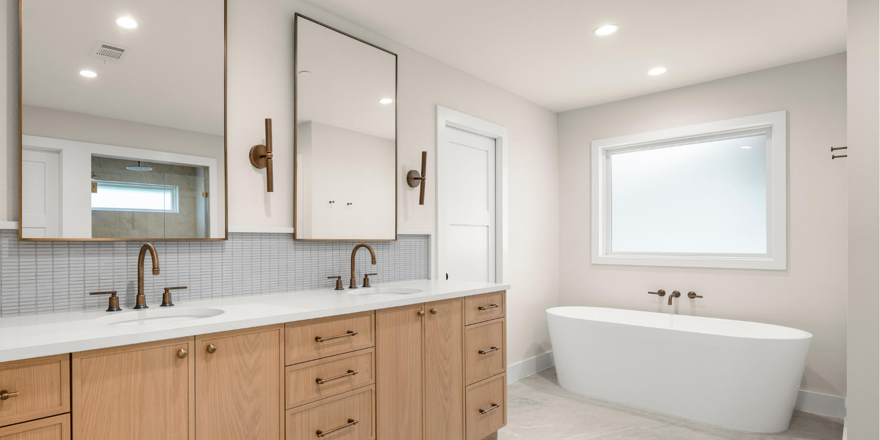 Bright modern bathroom with double vanity, wood cabinets, bronze fixtures, and a freestanding soaking tub